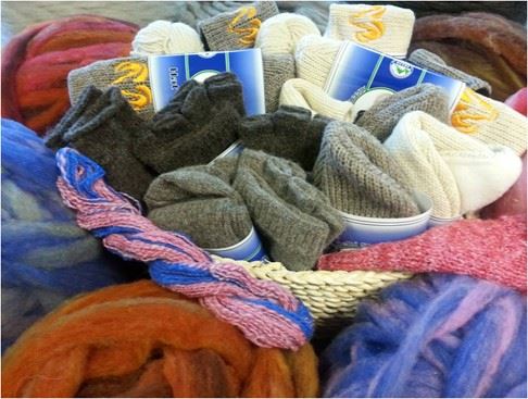 a variety of wool socks, hats, and yarn in a basket